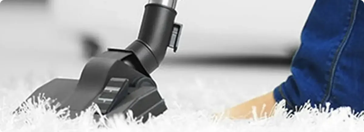 Close-up of a professional vacuuming a white carpet in Smyrna.